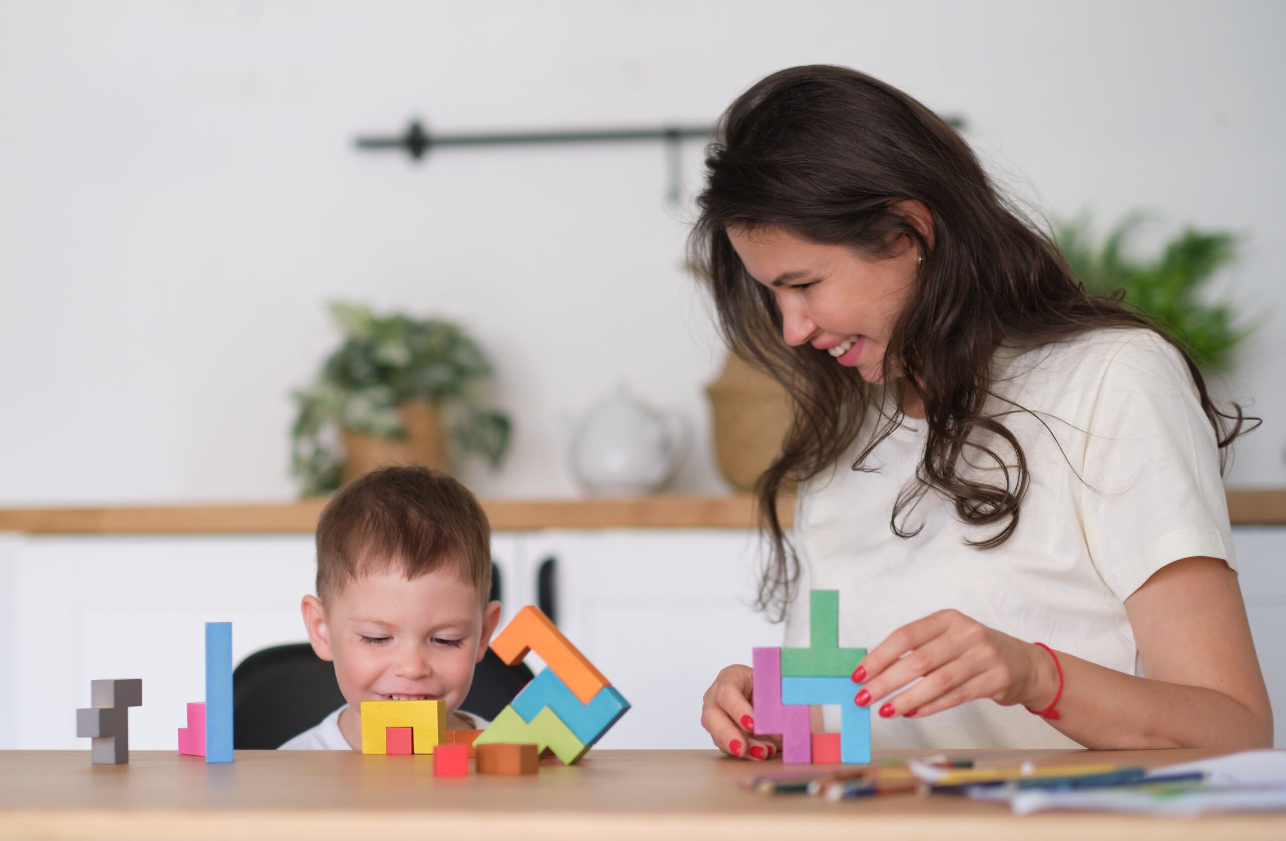 kid boy and mother playing educational toys at table at home.